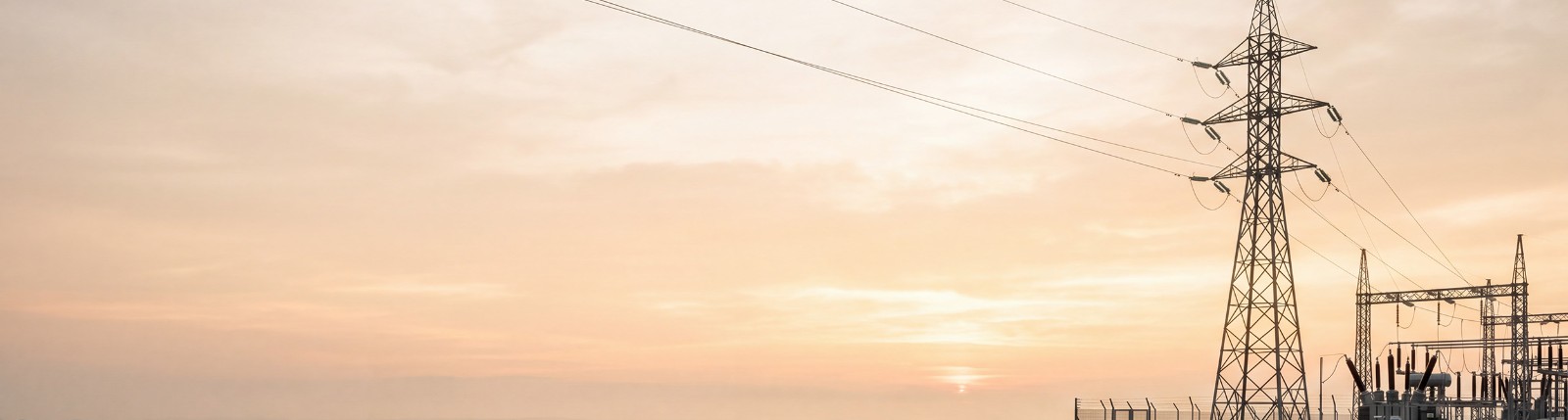 Transmission pylon and substation at sunrise